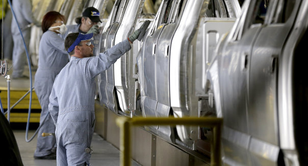 FILE - In this March 13, 2015 file photo, workers inspect the new aluminum-alloy body Ford F-150 trucks before they get painted at the company